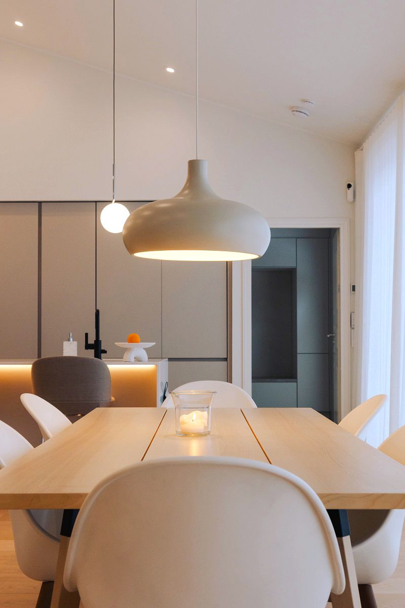 Lighting of an open dining room with spotlights, LED strip and hanging lamps.